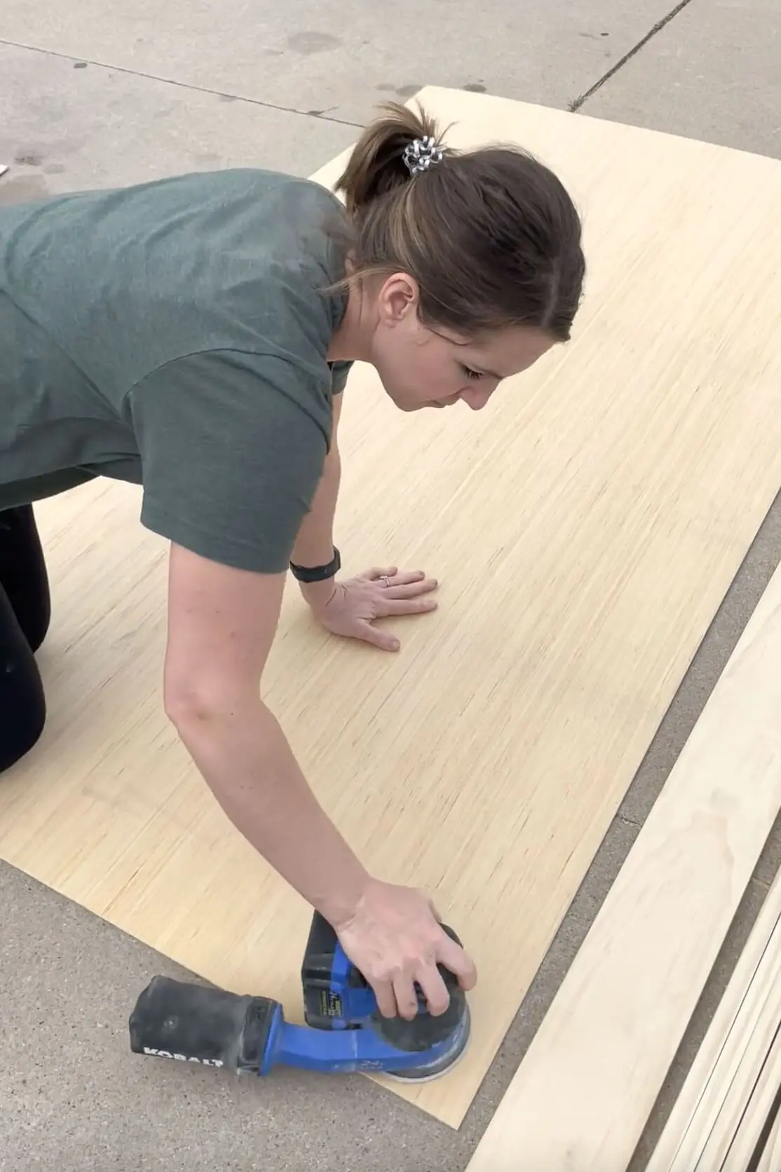 Sanding a sheet of plywood to prep for stain applicatioin.